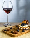 A glass of red wine and a cake with blueberry berries on a tray, with a fork and candy against a brick wall Royalty Free Stock Photo