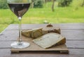 Glass of red wine and cheese on the cutting board on the old wooden table Royalty Free Stock Photo