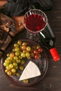 Glass of red wine with cheese and fresh grapes on wooden table Royalty Free Stock Photo