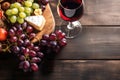 Glass of red wine, cheese and grapes on old wooden table with copy space Royalty Free Stock Photo