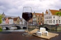 Glass of red wine with cheese snacks against stone bridge in Bruges, Belgium. Traditional bridge over canal in Brugge Royalty Free Stock Photo