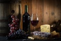 Glass of red wine cheeses grapesand barrel on brown wood Royalty Free Stock Photo