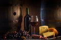 Glass of red wine cheeses grapesand barrel on brown wood Royalty Free Stock Photo