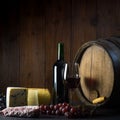 Glass of red wine cheeses grapesand barrel on brown wood Royalty Free Stock Photo