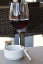 Glass of red wine and cigarette in a white ashtray on the table in a street cafe, summer, bad habits, alcoholism and Royalty Free Stock Photo