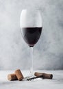 Glass of red wine with corks and opener on light background Royalty Free Stock Photo