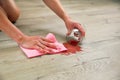 Glass of red wine fell on laminate, wine spilled on floor. A woman wipes the laminate from moisture Royalty Free Stock Photo