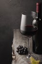 A glass of red wine, grapes and a bottle on an old wooden table Royalty Free Stock Photo