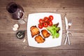 Glass of red wine, grilled meat on the white plate, tomatoes, le