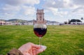 Glass of red wine in hand of traveler past the 16th century tower Belem, Lisbon of Portugal Royalty Free Stock Photo