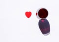 Glass of red wine with red heart and sparkling shadow on white background. Free copy space. Concept of love for good drinks, Royalty Free Stock Photo