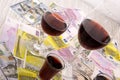 Glass of red wine and money on an old wooden table. Angle view, focus on the glass of red wine Royalty Free Stock Photo