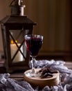 Glass with red wine. Near broken chocolate. Lantern with a candle in the background Royalty Free Stock Photo