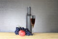 Glass of red wine near wine bottle next to apple and bunch of grapes Royalty Free Stock Photo