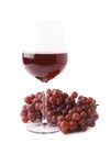 Glass of red wine next to a branch of grapes