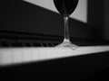 Glass of red wine on piano, black and white