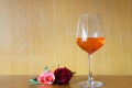 Glass of red wine, pink rose on wood table with wood wall on background