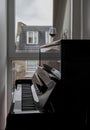 Glass of red wine placed on black piano by the window that looks out onto the brick house outside Royalty Free Stock Photo