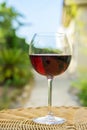 Glass of Red Wine on Rattan Wicker Table in Garden on Villa Mansion. Bright Summer Spring Sunny Day Vegetation Blue Sky. Authentic Royalty Free Stock Photo