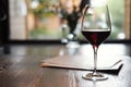 A Glass of red wine in restaurant or cafe on wooden table in front of window, romantic date, lunch relaxation. Royalty Free Stock Photo