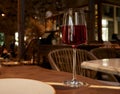 A glass of red wine on a restaurant table with illumination reflected in the glass and a blurred background Royalty Free Stock Photo