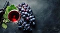 Glass of red wine, ripe vine grapes and wine bottle on dark stone background, top view. Winery agriculture, grape harvest concept. Royalty Free Stock Photo