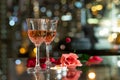 Glass red wine, roses, petals and candles on table with reflection, twinkling blurred city night lights in background, romantic Royalty Free Stock Photo