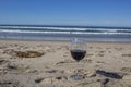 Glass of red wine on the sand on the beach overlooking the sea in a romantic atmosphere Royalty Free Stock Photo