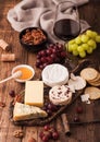 Glass of red wine with selection of various cheese on the board and grapes on wooden background. Blue Stilton, Red Leicester and Royalty Free Stock Photo