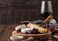 Glass of red wine with selection of various cheese on the board and grapes on wooden background. Blue Stilton, Red Leicester and