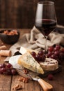 Glass of red wine with selection of various cheese on the board and grapes on wooden background. Blue Stilton, Red Leicester and Royalty Free Stock Photo