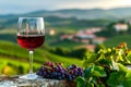 Glass of red wine is sitting on rock with bunches of grapes in front of it and orchard in the background. Generative AI Royalty Free Stock Photo