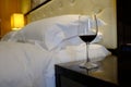 A glass with red wine stands on the bedside table and bed Royalty Free Stock Photo