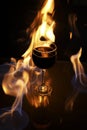 Glass of red wine on glass table with fire around it on black background, romantic photo