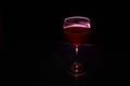 Glass of red wine on glass table with fire around it on black background, romantic photo Royalty Free Stock Photo