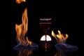 Glass of red wine on glass table with fire around it on black background, romantic photo