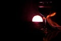 Glass of red wine on glass table with fire around it on black background, romantic photo Royalty Free Stock Photo
