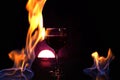 Glass of red wine on glass table with fire around it on black background, romantic photo Royalty Free Stock Photo