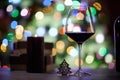 Glass of red wine on table with gift boxes. Christmas lights in the background Royalty Free Stock Photo