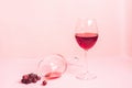 A glass of red wine on the table is turned upside down and a bunch of grapes on gentle pink background. Selective focus Royalty Free Stock Photo