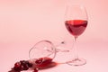 A glass of red wine on the table is turned upside down and a bunch of grapes on gentle pink background. Selective focus. Royalty Free Stock Photo