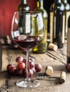 Glass of red wine on the table. Wine bottle and grapes at the ba Royalty Free Stock Photo