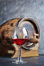 Glass with red wine for tasting and wooden barrel in dark cellar Royalty Free Stock Photo