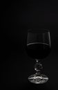 A glass of red wine. Red wine in a transparent glass with reflections. Black background.