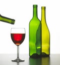 Glass of red wine with two empty bottles Royalty Free Stock Photo