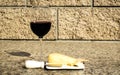 Glass of wine with cheddar cheese, small knife, and crackers on an outdoor table