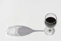 Glass of red wine on a white background with dark deep shadow