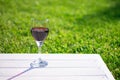 Glass with red wine on a white wooden table on a background of grass. Copy space Royalty Free Stock Photo