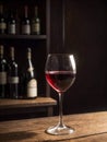 Glass of red wine on wooden table in wine cellar with bottles in background Royalty Free Stock Photo