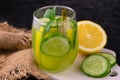 A glass of refreshing drink with cucumber, lemon and mint on a black background. Close-up. Royalty Free Stock Photo